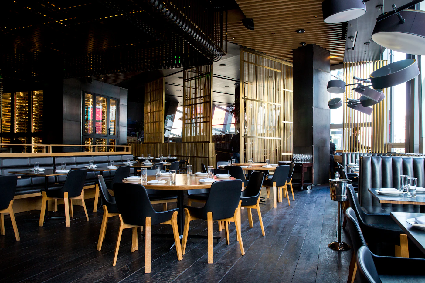 A warmly lit restaurant dining room with dark wood tables